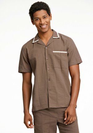 Brown short-sleeve shirt with textured fabric, featuring a notched collar, front pocket, and contrasting white accents and buttons.