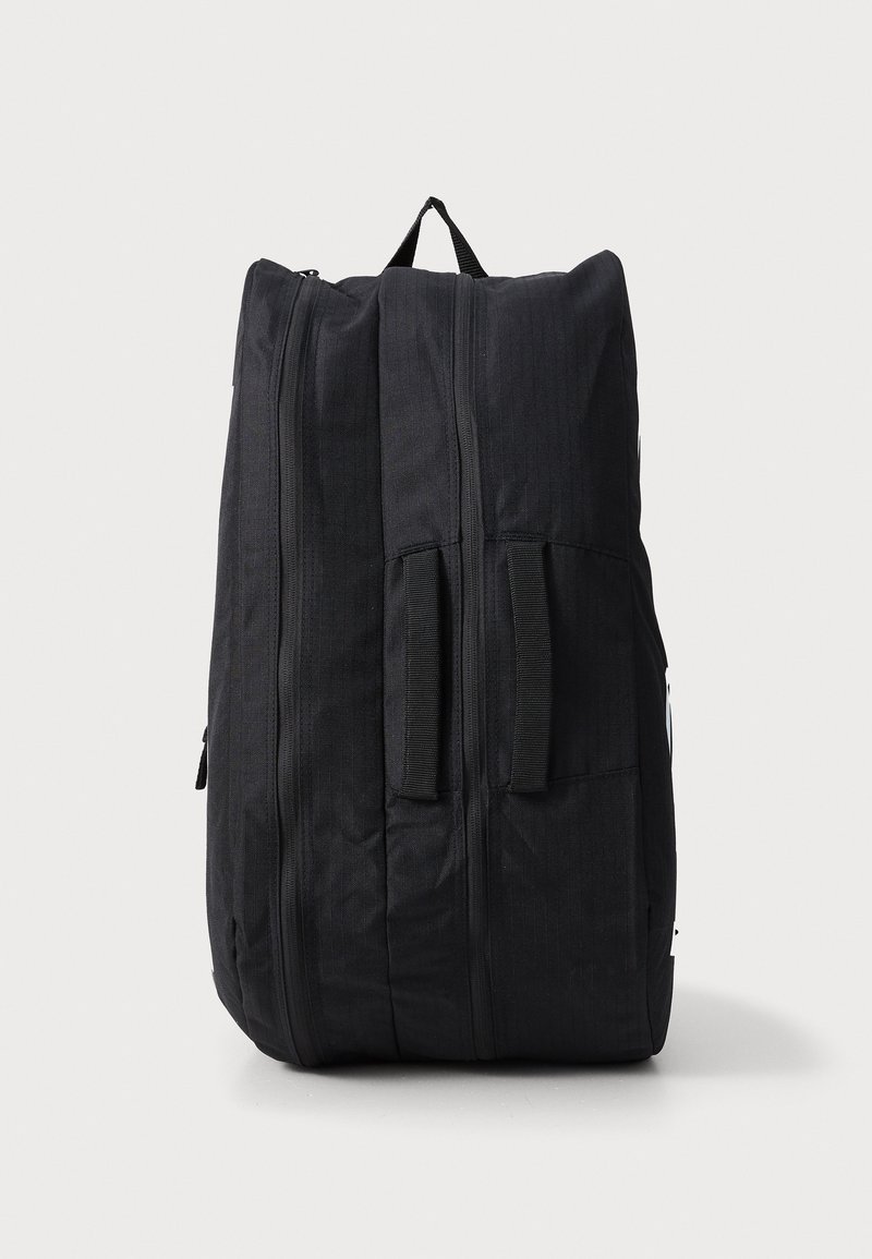 Mochila negra hecha de tejido duradero. Presenta dos asas laterales, cremalleras verticales y un acabado de textura suave. Diseño sencillo sin patrones.