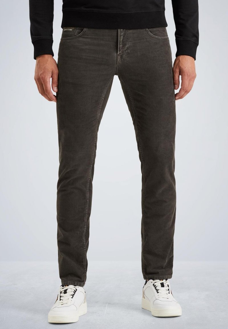 Pantaloni in velluto scosso grigio scuro con vestibilità slim, dotati di tasche frontali e cuciture a contrasto, abbinati a sneaker bianche.