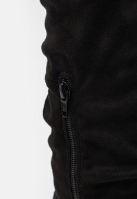 Tissu en suède noir avec une texture douce, doté d'une fermeture éclair latérale en finition noire pour un maintien sécurisé.