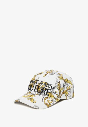 Cappellino bianco con un motivo floreale giallo ornate, dotato di un logo ricamato nero che recita "Versace Jeans Couture." Design con visiera curva.
