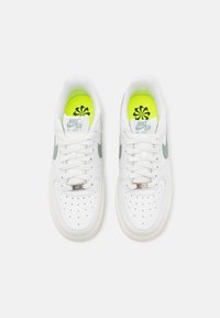 Białe skórzane sneakersy o gładkiej teksturze, z zielonymi akcentami, perforowanym noskiem oraz jaskrawozielonymi wkładkami z kwiatowym wzorem.