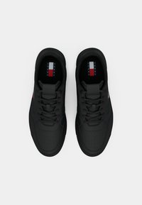 Paire de baskets noires à lacets vue de dessus avec une zone des orteils perforée et un logo Tommy Jeans à l'intérieur du talon.