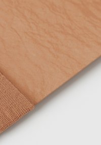 Tela color arena con una superficie texturizada, que presenta una sección suave y un borde blando y ligeramente difuso en contraste.