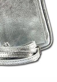 Zilveren metallic leren handtas met een gestructureerd uiterlijk, hoek met gestikte randen en een lusvormige banddetail op een witte achtergrond.