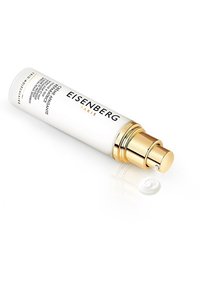 Eisenberg Paris kräm i en vit, cylindrisk flaska med en guldpump. En liten sväng av krämen ligger på en reflekterande yta.