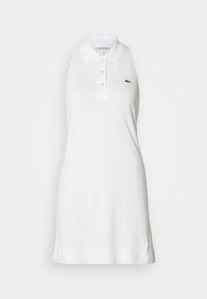 Robe polo blanche sans manches avec col et trois boutons, arborant un petit logo de crocodile vert sur la poitrine gauche.