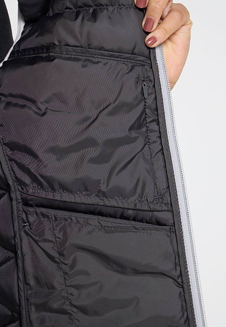 Schwarze Steppjacke innen, ausgestattet mit einem glatten, leichten Stoff, der eine Reißverschluss-Tasche und zwei offene Taschen für die Aufbewahrung bietet.