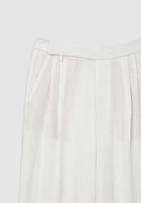 Pantalon plissé blanc en tissu texturé, doté de poches latérales et d'une taille plate. Design épuré sans attaches visibles.