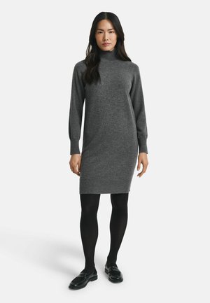 Gray turtleneck dress made of a soft knit fabric, fitted design, knee-length with ribbed cuffs and hem, paired with black tights and loafers.