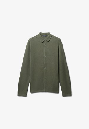 Chemise olive verte à boutons, fabriquée en tissu texturé. Dotée d'un col, de manches longues et d'un ourlet droit avec six boutons assortis.