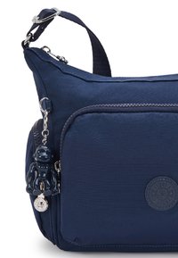 Borsa di tessuto blu navy con superficie testurizzata, tasche con cerniera e un charm a forma di scimmia nera staccabile con dettagli in argento.