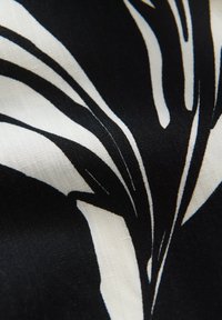 Schwarzer Stoff mit weißen abstrakten Blatttypen, der eine glatte Textur und ein glänzendes Finish aufweist, mit kontrastierenden Farben und einem fließenden Design.