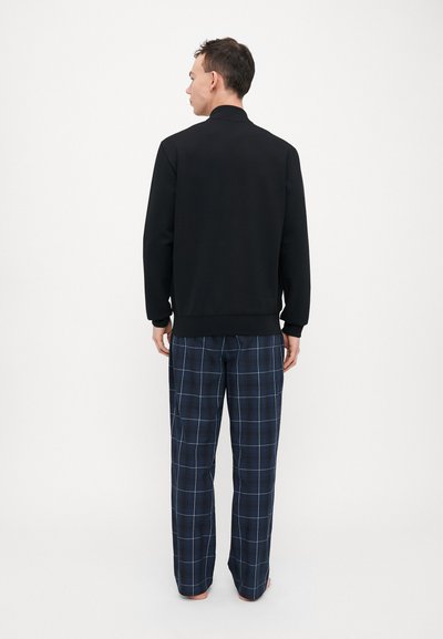 Black sweatshirt with long sleeves, paired with loose-fitting, navy plaid pajama pants featuring white and light blue grid lines.