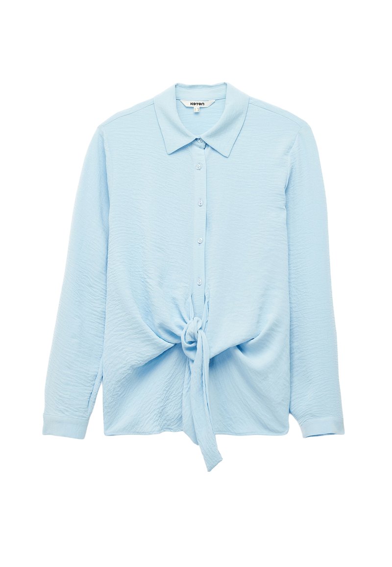 Lichtblauwe lange mouwen button-up shirt met een gestructureerde stof, puntige kraag en een geknoopte voorzijde. Heeft vijf knopen op de knoopsluiting.