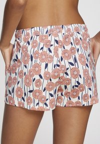 Floral-patterned shorts with a soft, lightweight fabric; features pink and navy flowers against a cream background, elastic waistband, side pockets.