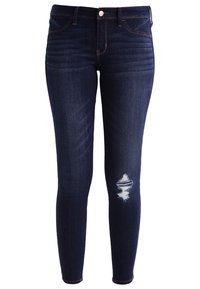 Skinny jeans i mörkblå denim, med en slitning vid knät och subtila sömmar. Klassisk femfickdesign med kopparaccenter.