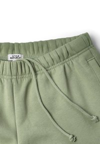 Pantalons de survêtement en coton vert avec une taille élastique, cordon de serrage ajustable, poches latérales et une étiquette indiquant "STYLE REPUBLIC". Texture lisse.