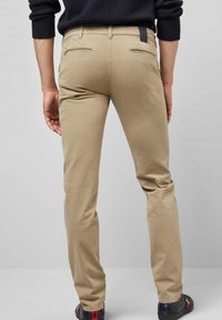 Beige katoenen chino's met een slim fit, voorzien van twee achterzakken en een merketiket. Soepele textuur en minimalistisch ontwerp.