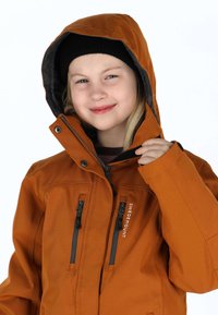 Orange wasserdichte Jacke mit Kapuze, ausgestattet mit zwei Reißverschlusstaschen, grauem Futter und schwarzen Akzenten. Über einem dunklen Oberteil getragen.