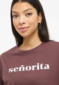 Bordowa koszulka z napisem "señorita" w wyraźnym, białym kroju pisma. Gładka bawełniana tkanina z klasycznym okrągłym dekoltem.