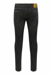 Vaqueros skinny de mezclilla negra con una textura suave, diseño de cinco bolsillos y un parche de cuero en la cintura. Sin adornos visibles.