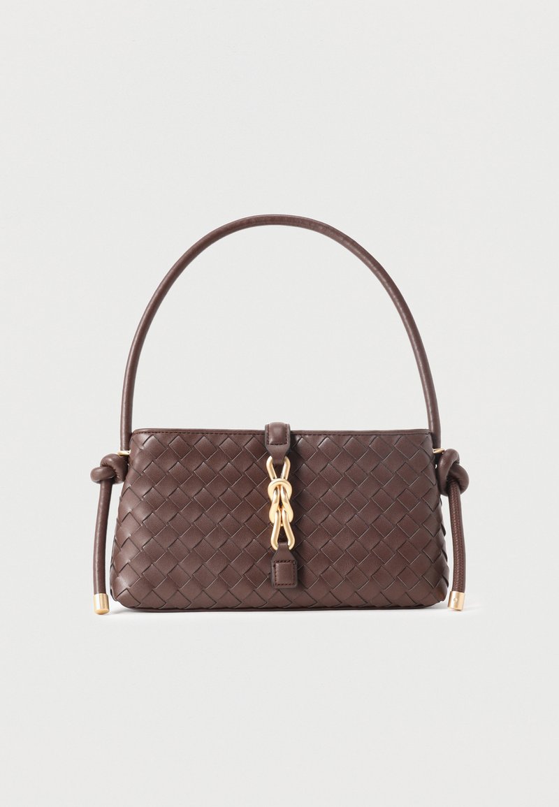 Sac à main en cuir tressé marron foncé avec une poignée incurvée, un détail en chaîne dorée au centre et des nœuds aux extrémités de la poignée sur un fond clair.