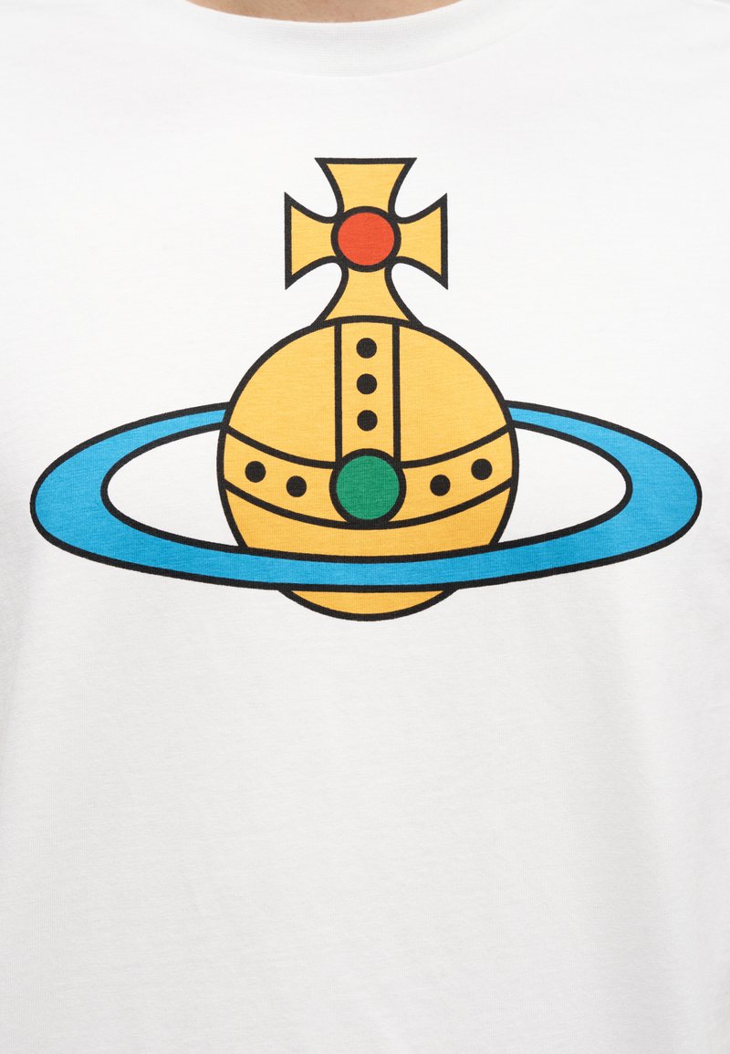 Hvid bomulds T-shirt med et grafisk design af en gul kugle med et kors på toppen, omgivet af en blå ring og grønne accenter.