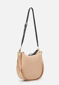 Læder skuldertaske i lys beige med en buet form; har en sort justerbar rem og gulddetaljer i hardware. Tekstureret finish.