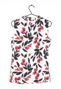 Débardeur fleuri en tissu blanc avec un motif de fleurs noires et rouges. Le dos présente une petite ouverture en forme de goutte avec un col froncé.