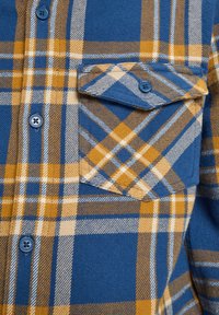 Modrá a oranžová kockovaná košeľa s prednou časťou, gombíkovou vreckou a viditeľnými gombíkmi v strede.