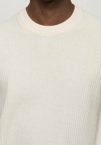 Jasno beżowy sweter prążkowany z okrągłym dekoltem i teksturowanym materiałem. Miękka dzianina z subtelnym wzorem i klasycznym krojem.