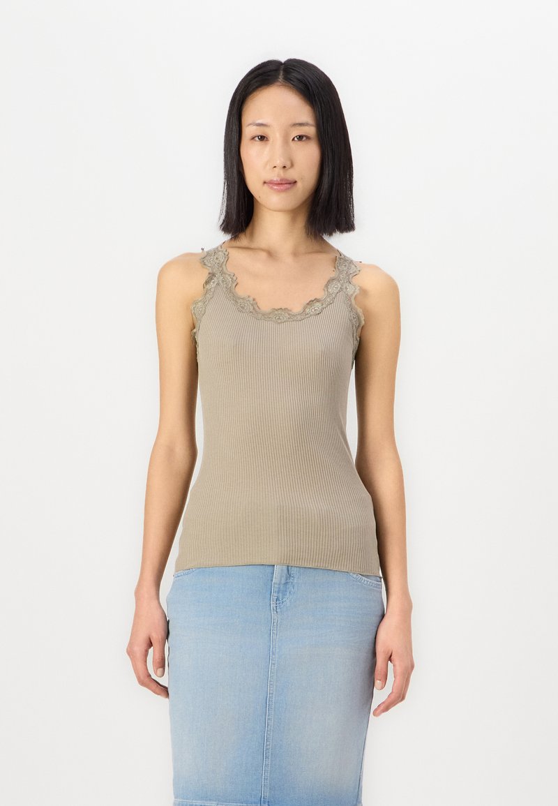 Kakifarvet ribbestrikket tanktop med blondekant langs halsen, sammen med et lyseblått denimskjørt. Enkel, tettsittende design.