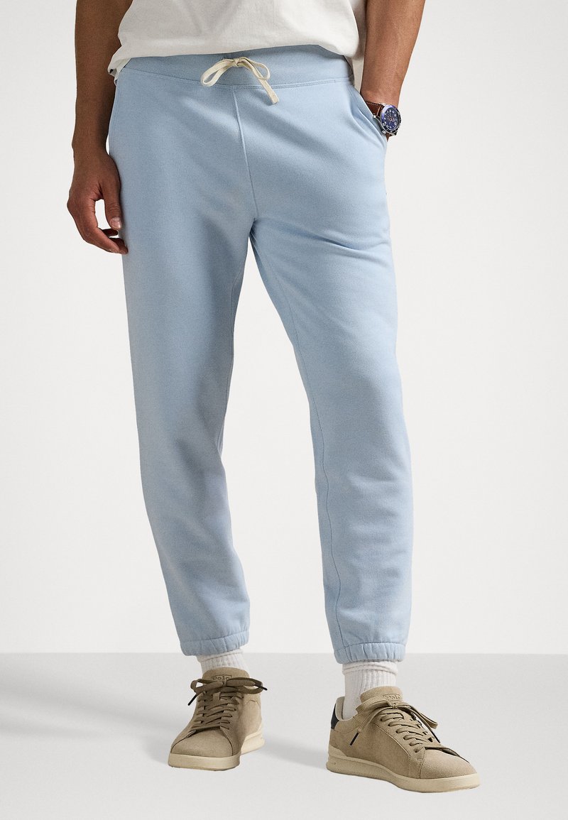 Pantalon de survêtement bleu clair avec une taille à cordon, des poignets resserrés et des poches latérales, fabriqué en tissu doux et texturé.