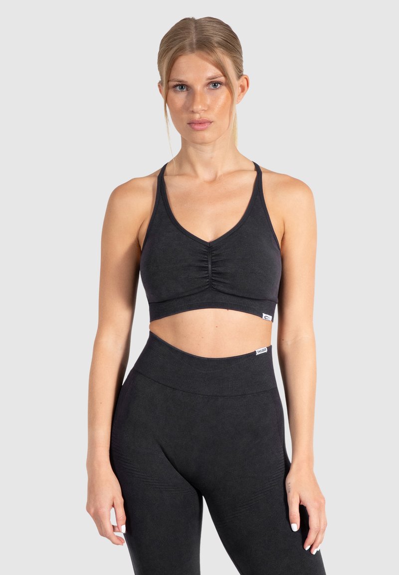 Zwarte sportbeha in cropped stijl met een v-hals ontwerp en een geplooide voorkant. Gemaakt van een textuurstof met dunne bandjes en een naadloze afwerking.