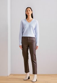 Lyseblå v-hals sweater, lange ærmer, lavet af blødt materiale; parret med brune tætsiddende bukser og cremefarvede ankelstøvler med blokhæle.