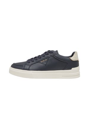 Niski czarny sneaker z białą podeszwą, sznurowanym wzorem, beżową łatką na pięcie i złotym logo „REPLAY” z boku.