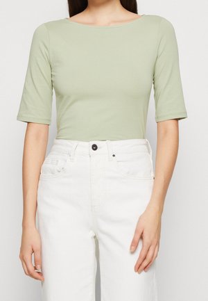 Jasnozielony, dopasowany top z szerokim dekoltem i rękawami do łokcia, zestawiony z białymi spodniami z wysokim stanem, o minimalistycznym designie.