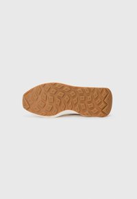 Ljust färgad sneakersula med en texturerad gummiyta, prydd med ett diamantmönster och en lätt kurvatur för grepp och flexibilitet.