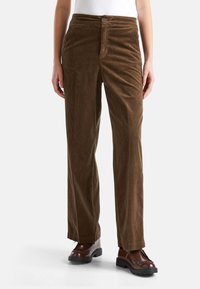 Brązowe spodnie w korduroy z prostymi nogawkami, z zapięciem na guzik, umiarkowaną teksturą oraz kieszenią po obu stronach.