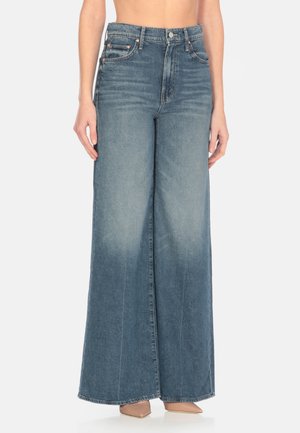 Jeans in denim a gamba larga in lavaggio azzurro chiaro. Presentano una vita alta, dettagli sfumati e un design tradizionale a cinque tasche. Tessuto morbido e texturizzato.