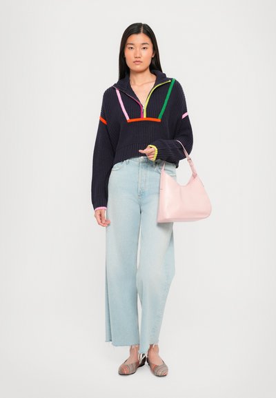 Marineblauwe cropped sweater met kleurrijke strepen, lichtblauwe wijde jeans, roze handtas en gestreepte ballerina's. Glad textuur en ontspannen pasvorm.