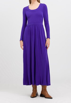 Robe maxi violette à manches longues en tissu doux, avec un corps ajusté et une jupe évasée, présentant un col rond et des froncements subtils à la taille.