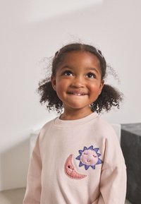 Ljusrosa sweatshirt med broderade sol- och måndesigner i lila och rosa. Mjukt tyg med avslappnad passform och rund halsringning.