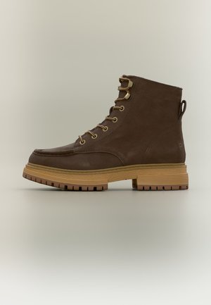 Bottine marron en cuir à lacets avec semelle en caoutchouc couleur fauve et languette à l’arrière, présentée de profil sur un fond neutre.