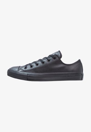 Juoda oda žema sneaker'io su apvaliu pirštu, plokščiomis raišteliais, tekstūruota viršutine dalimi, guma padais ir klasikiniu siuvimo detalėmis palei kraštus.