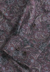 Hemdärmel mit schwarzen Knöpfen, versehen mit einem lila Paisleymuster und floralen sowie Blattdesigns in Blau, Gelb und Dunkelgrün.