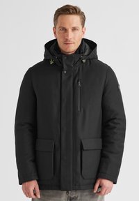 Schwarze isolierte Jacke mit Kapuze, ausgestattet mit einer Reißverschlusstasche auf der Brust, zwei Fronttaschen mit Klappe und kontrastierenden Hardware-Akzenten.