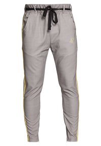 Grijze pantalon met krijtstrepen, voorzien van een elastische tailleband, een zwart koordje, gele zijstrepen en twee zakken. Heeft een logo aan de voorkant.