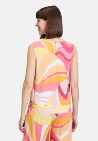Satynowy top bez rękawów z wielokolorowymi falami w odcieniach różu, żółci i bieli. Posiada zapięcie na guziki i marszczony dół. Miękka tekstura.